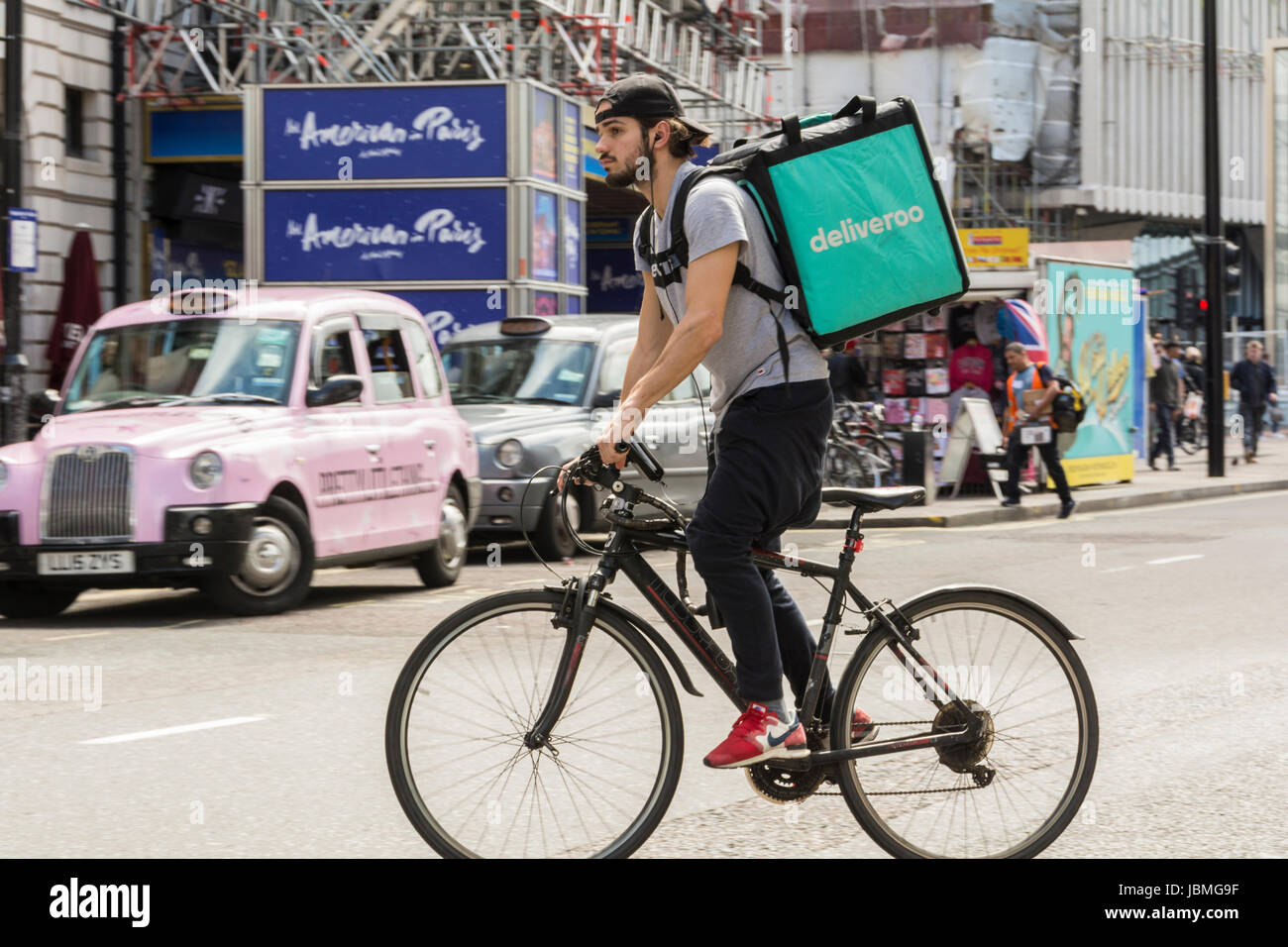 Ein Deliveroo-Radfahrer auf seinem Fahrrad im Verkehr auf der Tottenham Court Road, im Zentrum von London, England, Großbritannien Stockfoto