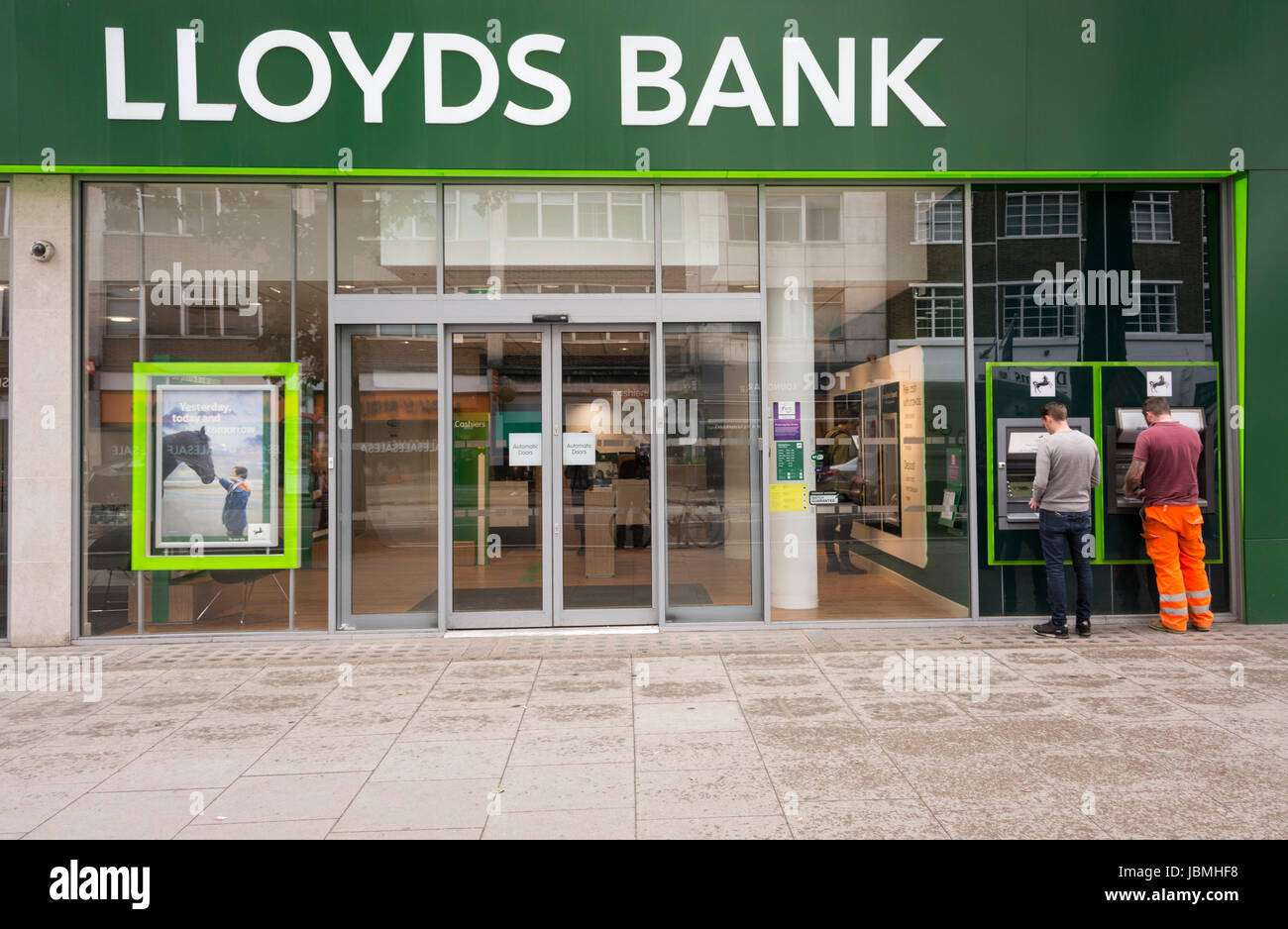 Zwei Männer, die Geldautomaten außerhalb der Lloyds Bank an der Tottenham Court Road, London, England, Großbritannien, benutzen Stockfoto
