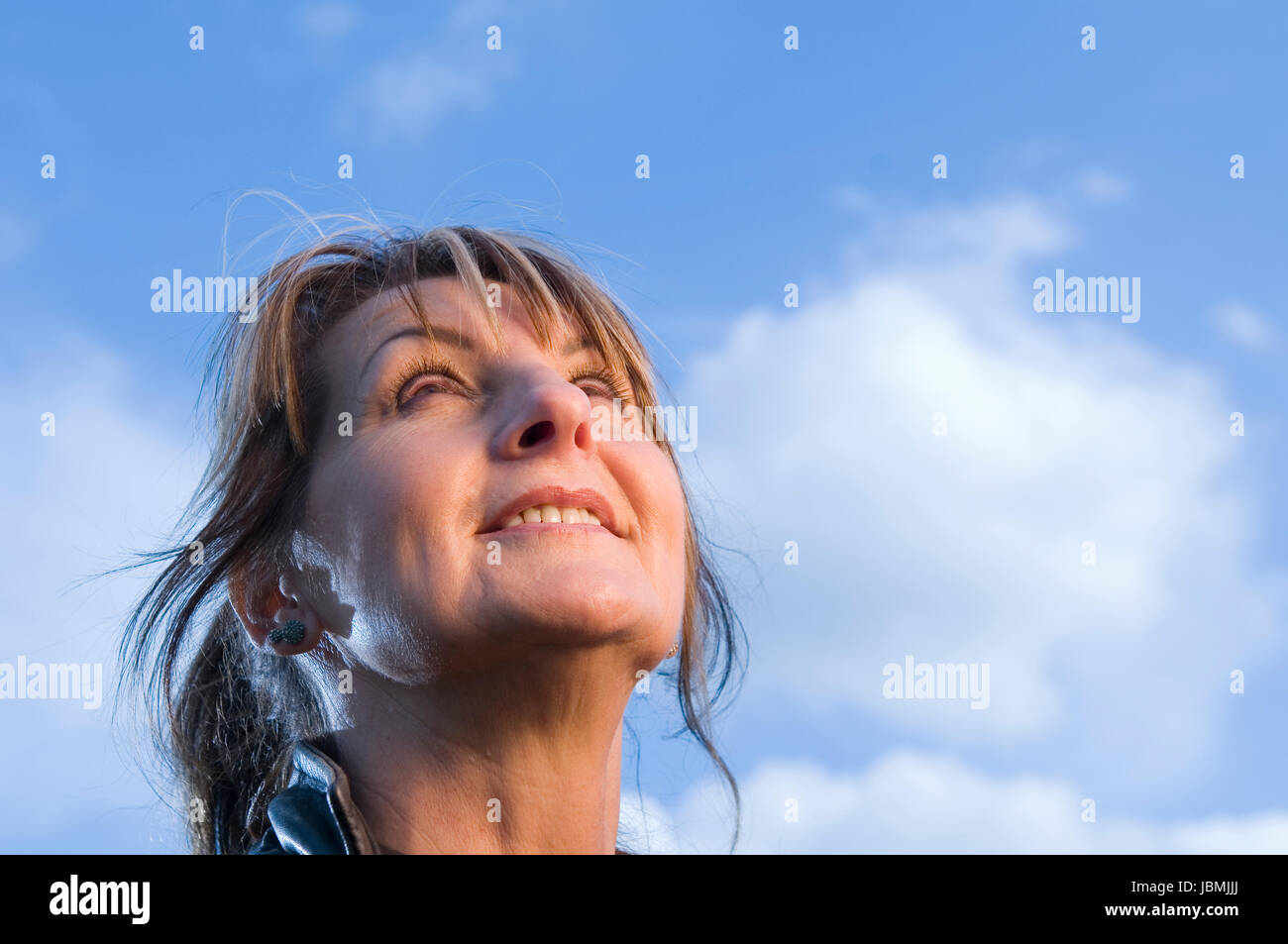 Seitliches Nahaufnahme Einer Frau Mittleren Alters Verträumt Nach Oben in Den Blauen Himmel schauend Stockfoto