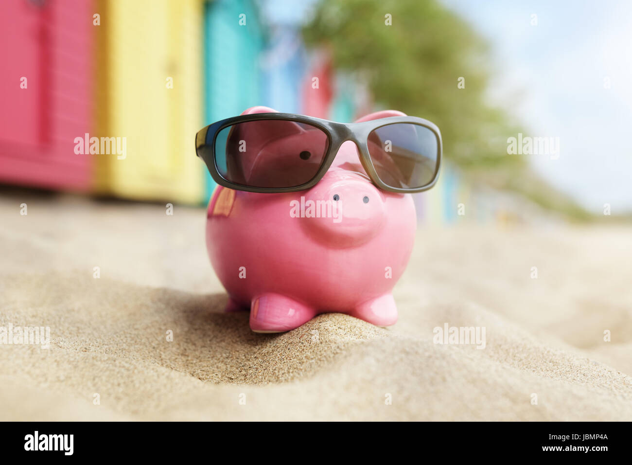 Sparschwein auf Sand Strandurlaub mit Sonnenbrille und Baden-Boxen Stockfoto