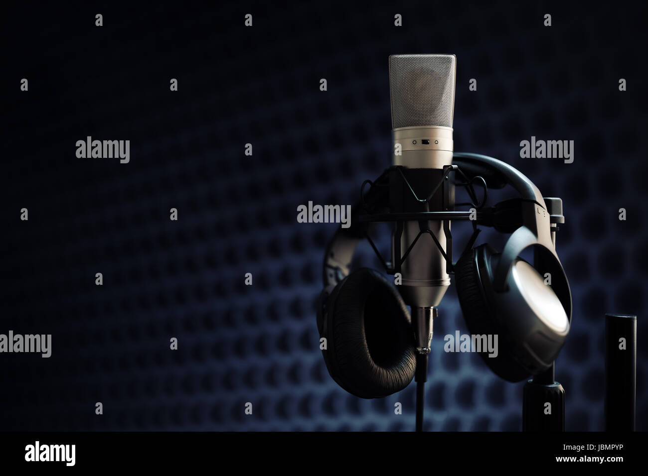 Studio-Mikrofon und Kopfhörer auf Mikrofonständer vor grauem Hintergrund Stockfoto