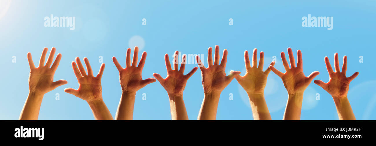 Die erhobenen Hände auf einem blauen Himmelshintergrund mit Textfreiraum Stockfoto