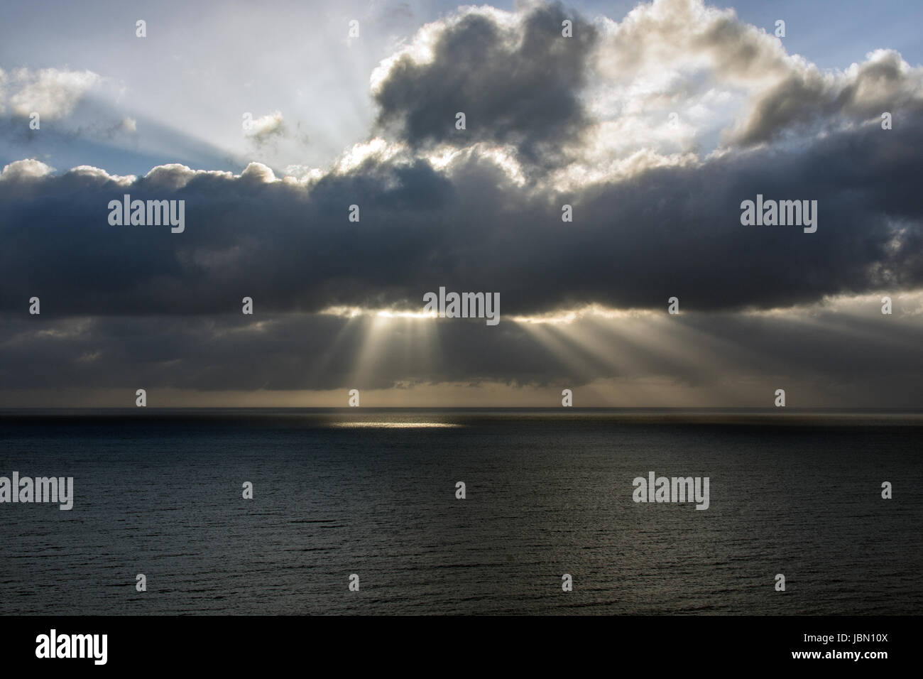 Ein Foto der Cardigan Bay vor der Küste von Aberystwyth. Die Sonnenstrahlen durch die Wolken kommen und das Meer leuchten. Stockfoto