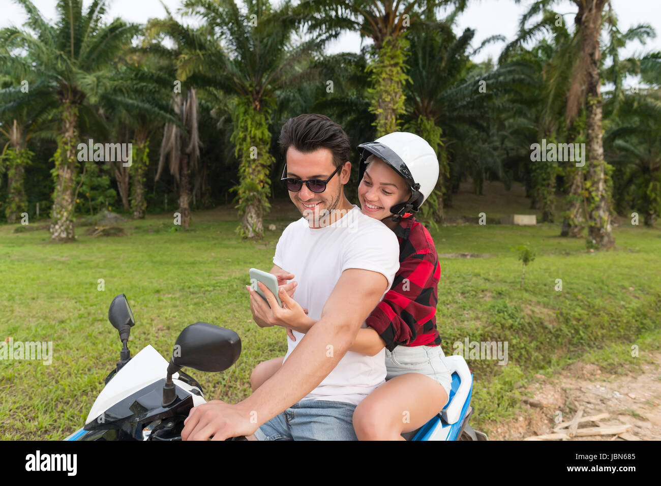 Paar auf Motorrad, Smart junger Mann und Frau mit Zelle Telefon Reise mit Fahrrad auf Tropical Forest Road Stockfoto