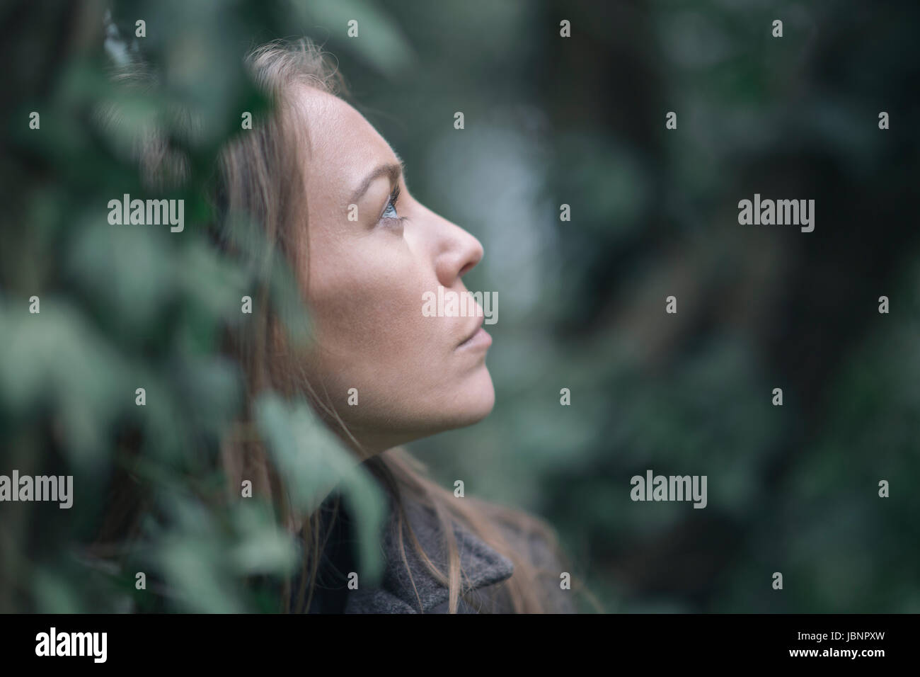 Frau hinter Efeublätter Stockfoto