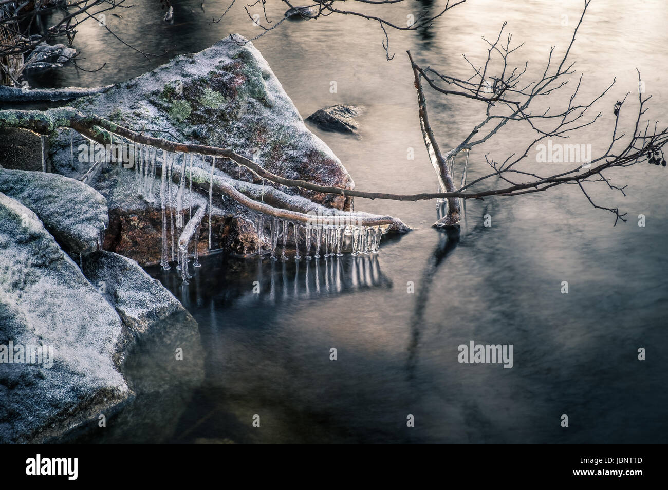 Malerische Landschaft mit Eiszapfen und See im Winterabend Stockfoto