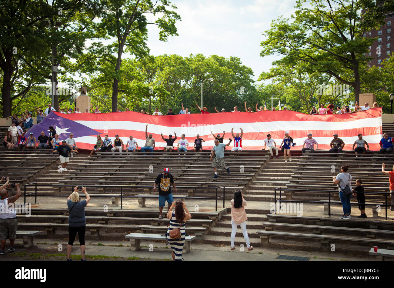 Eine riesige Puerto-ricanische Flagge wird während einer öffentlichen Demonstration von einer Menge hochgehalten, die Solidarität, Patriotismus und kulturelle Identität zeigt. Stockfoto