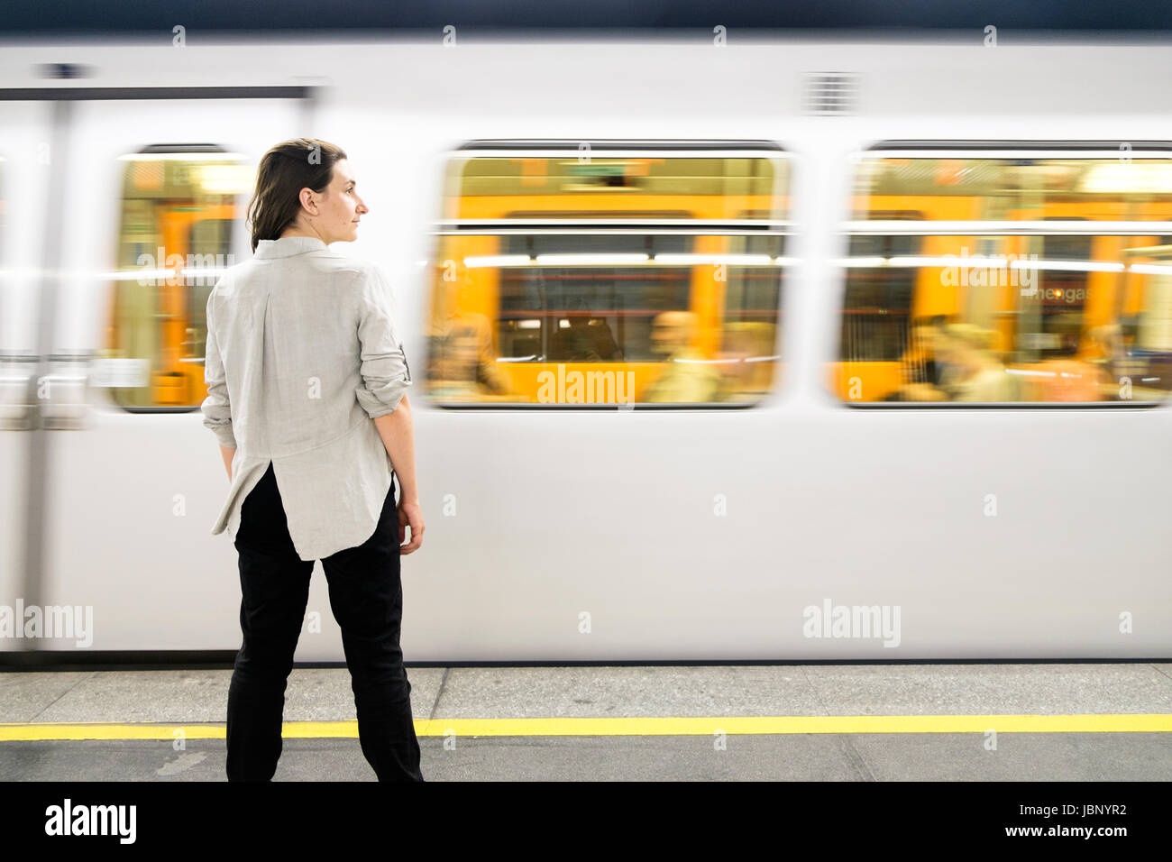 Eine Frau stand auf der Plattform einer U-Bahnstation (u-Bahn) Station in Wien, als ein Zug kommt. Stockfoto