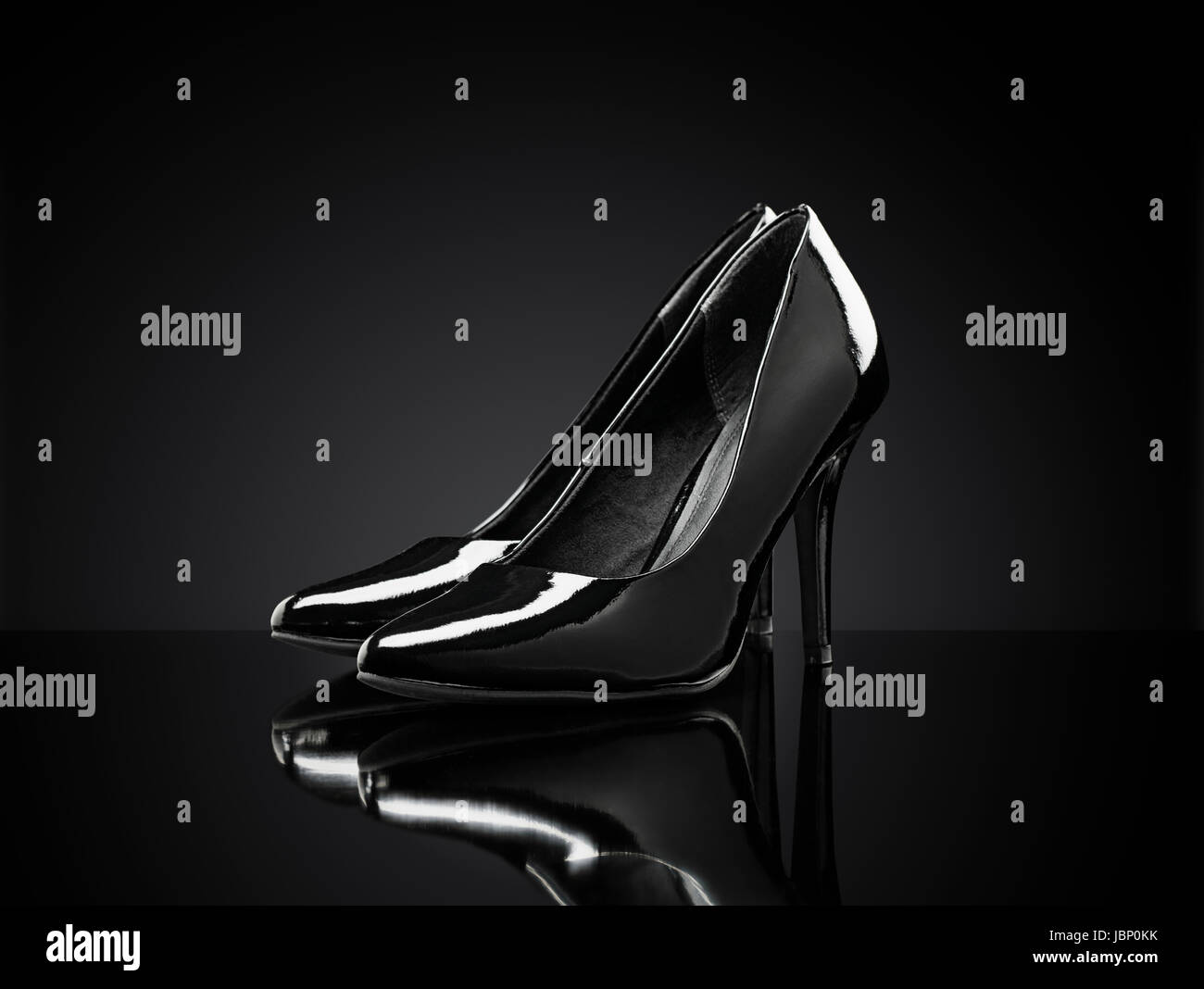 Schwarze glänzende Stiletto Heels Pumps auf schwarzen reflektierenden Hintergrund. Stockfoto