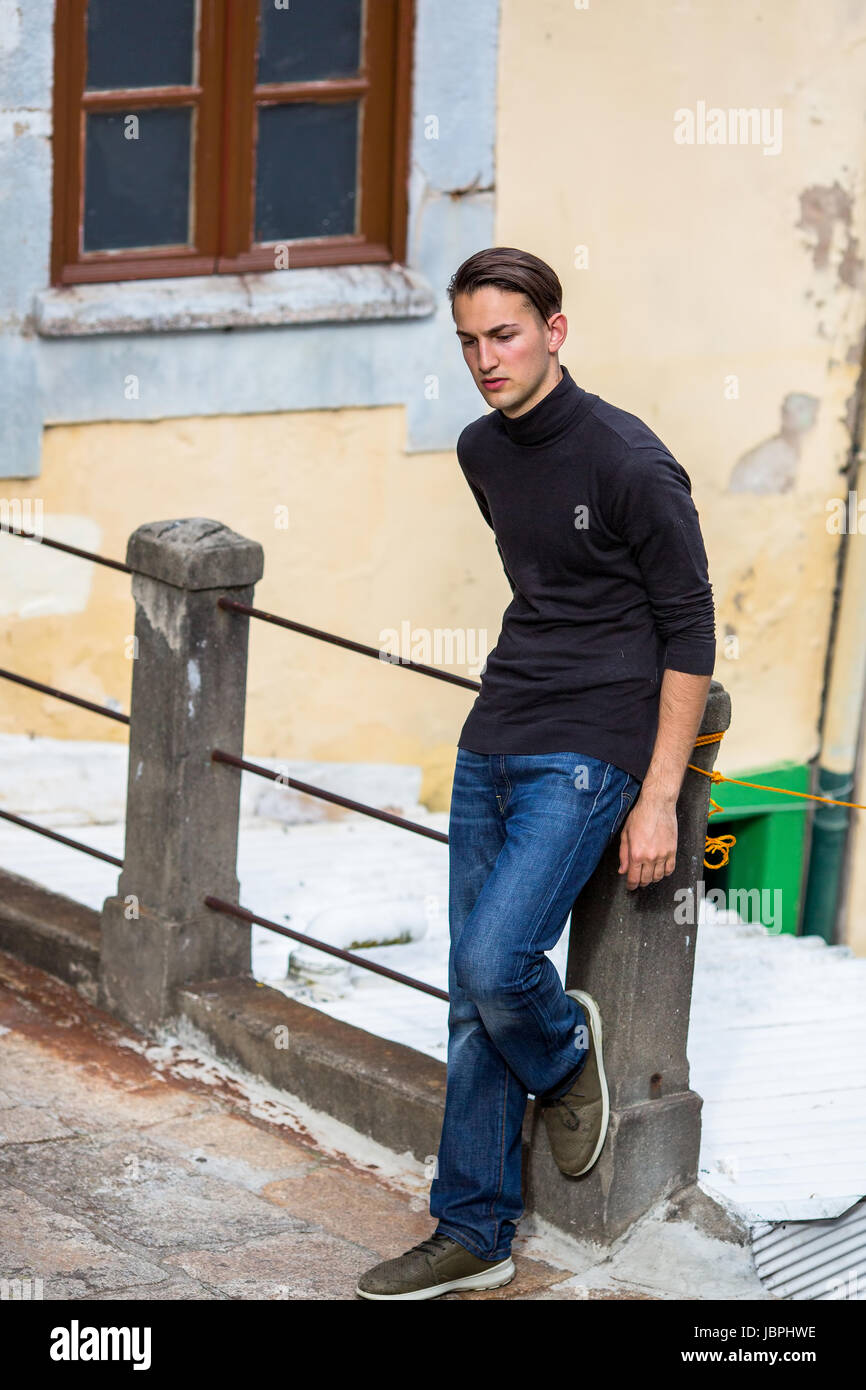 Schöner junger Mann steht in Straße der Altstadt. Stockfoto