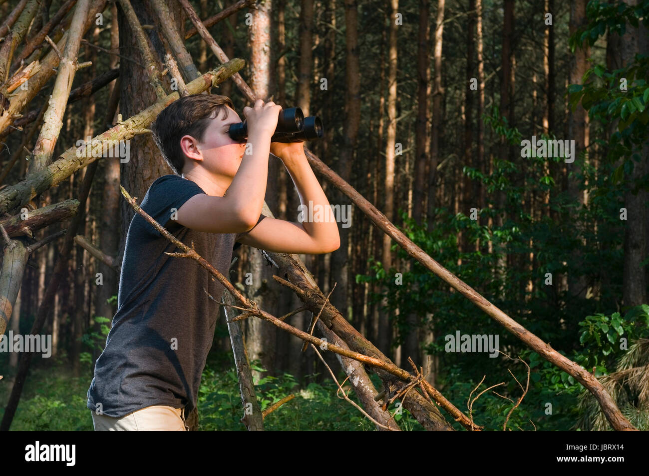 Seitliche Oberkörper-Ansicht Eines 13jährigen Männlichen Teenager Im Wald Durch Ein Fernglas schauend Stockfoto