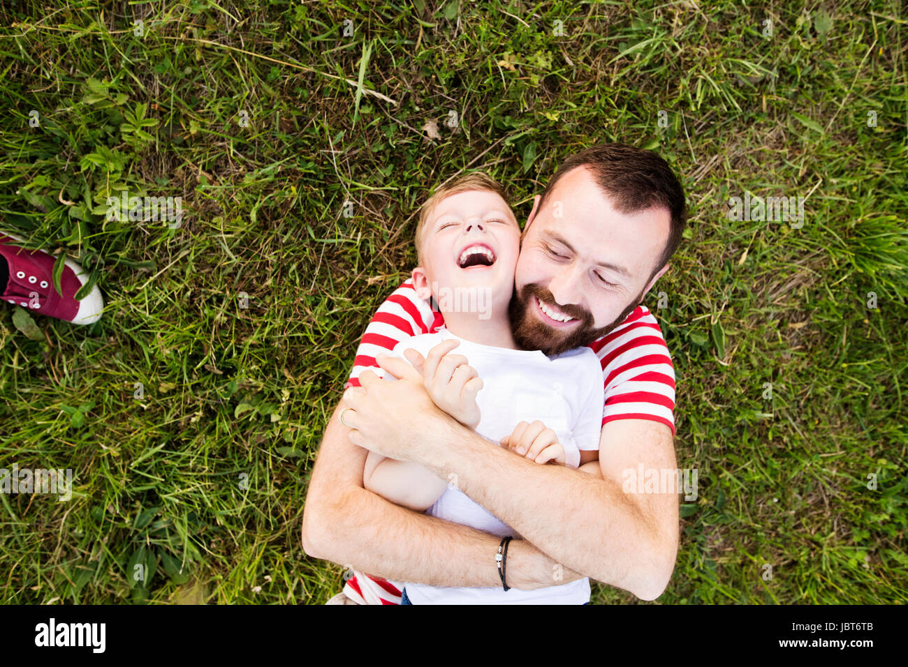 Hipster Vater und kleinen Sohn auf der grünen Wiese liegen. Sommertag. Stockfoto