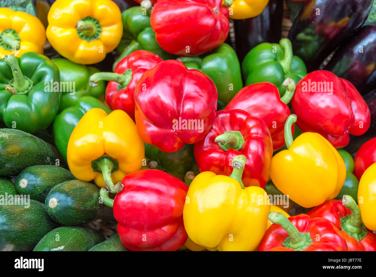 Bunte Gemüse-Hintergrund auf einem Markt. Gelbe, grüne und rote Paprika, Zucchini und Auberginen, Sommer-Gemüse-Konzept Stockfoto
