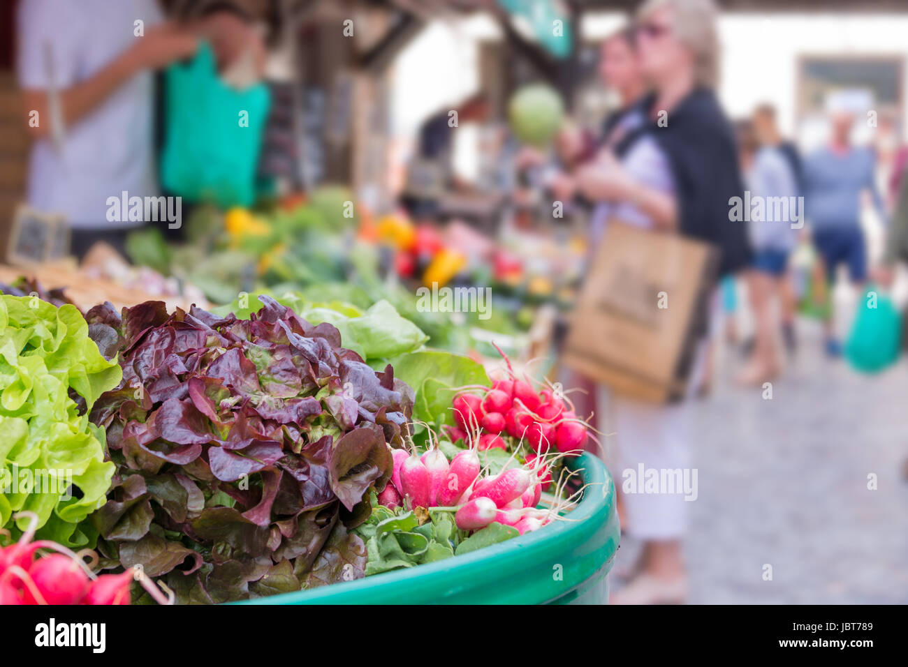 Outdoor-frische Lebensmittel-Markt im Sommer - Marktstand mit grünem Salat, Radieschen und Gemüse, unkenntlich Menschen im Hintergrund, Frankreich Stockfoto