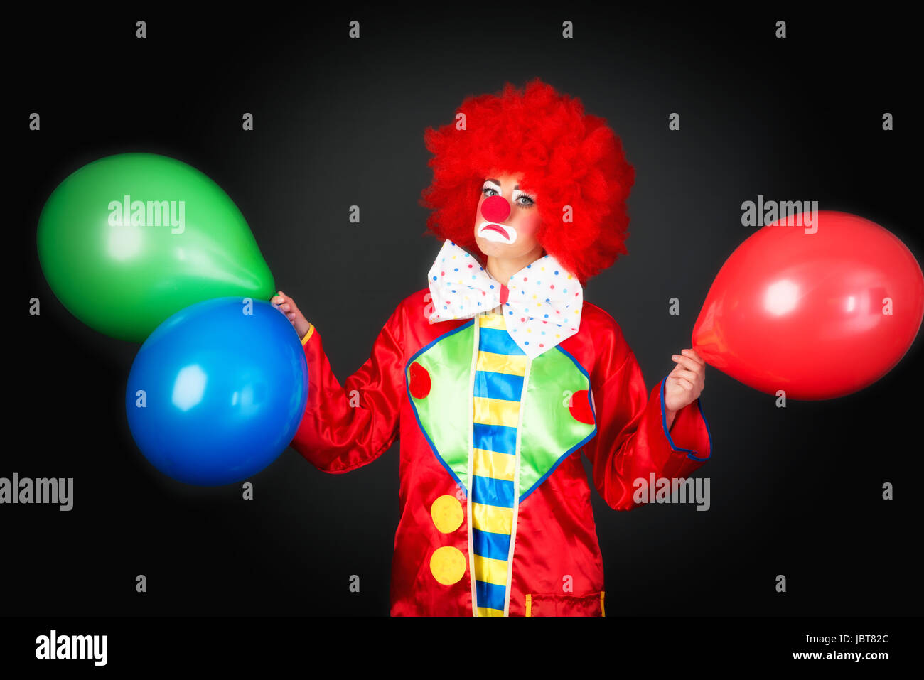 Trauriger Clown mit Luftballons Stockfoto