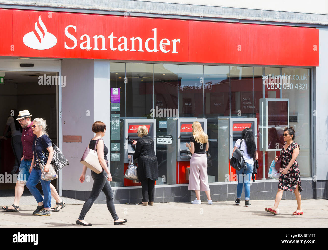 Santander Bank in eine UK-Hauptstraße mit Menschen mit Geldautomaten. Stockfoto