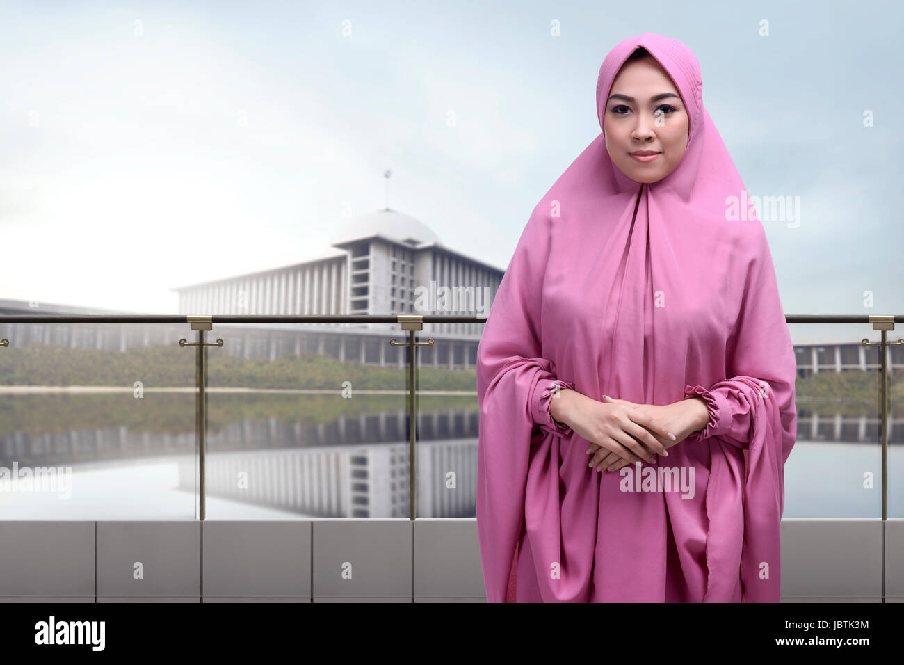 Religiöse muslimische Asiatin tragen Schleier mit umklammern Hand stehend vor Moschee-Hintergrund Stockfoto