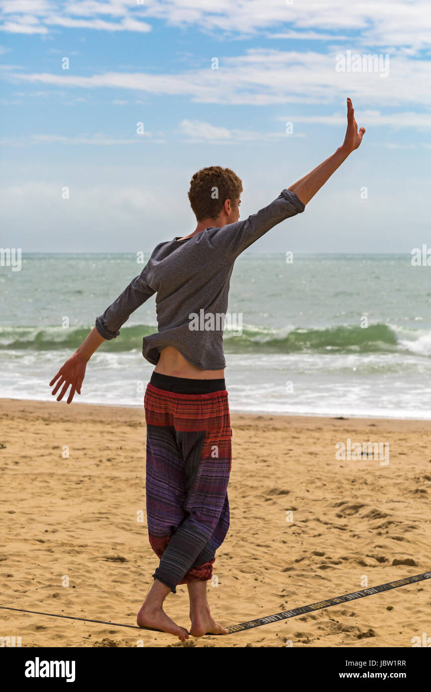 Mann auf Gibbon Jibline Slackline Slacklinen Balanceakt am Strand von Bournemouth, Dorset im Juni Stockfoto