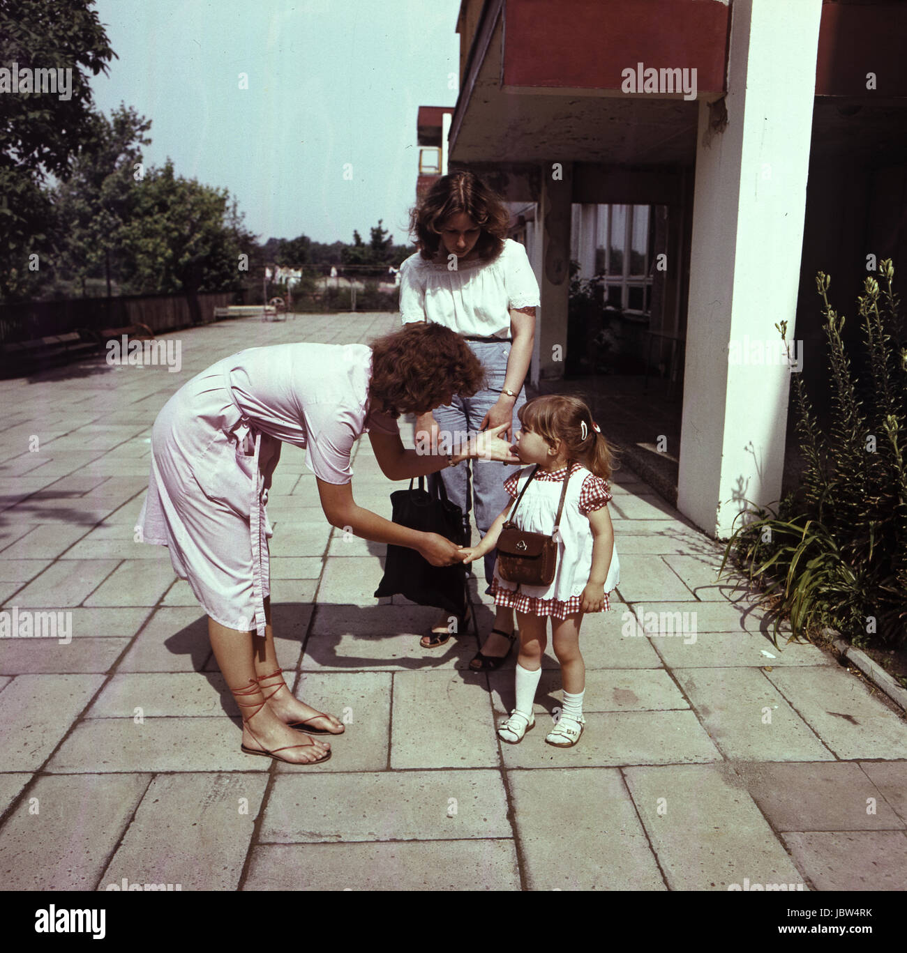 Weimar, DDR, Kindergärtnerin begrüßt ein kleines Mädchen in Gegenwart ihrer Mutter Stockfoto