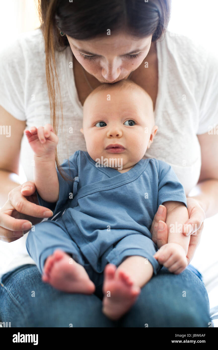 Mutter mit Baby sitzend auf Schoß, küßte ihn am Kopf Stockfoto