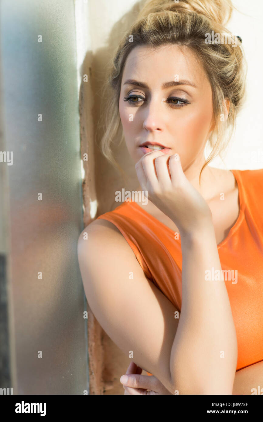 Schöne junge nachdenkliche blonde Frau aus dem Fenster Stockfoto