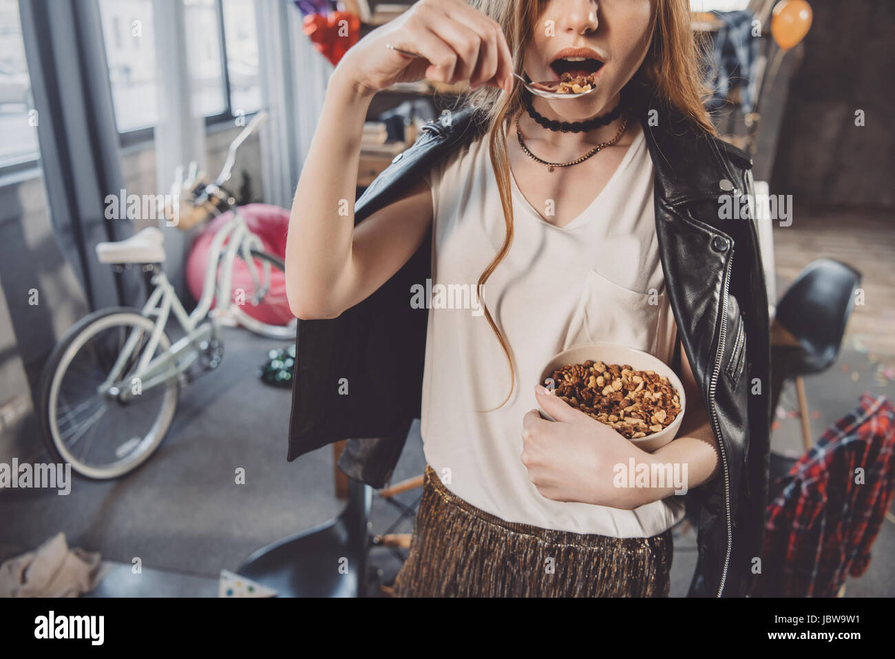 Frau Essen Cornflakes in unordentlichen Zimmer nach party Stockfoto