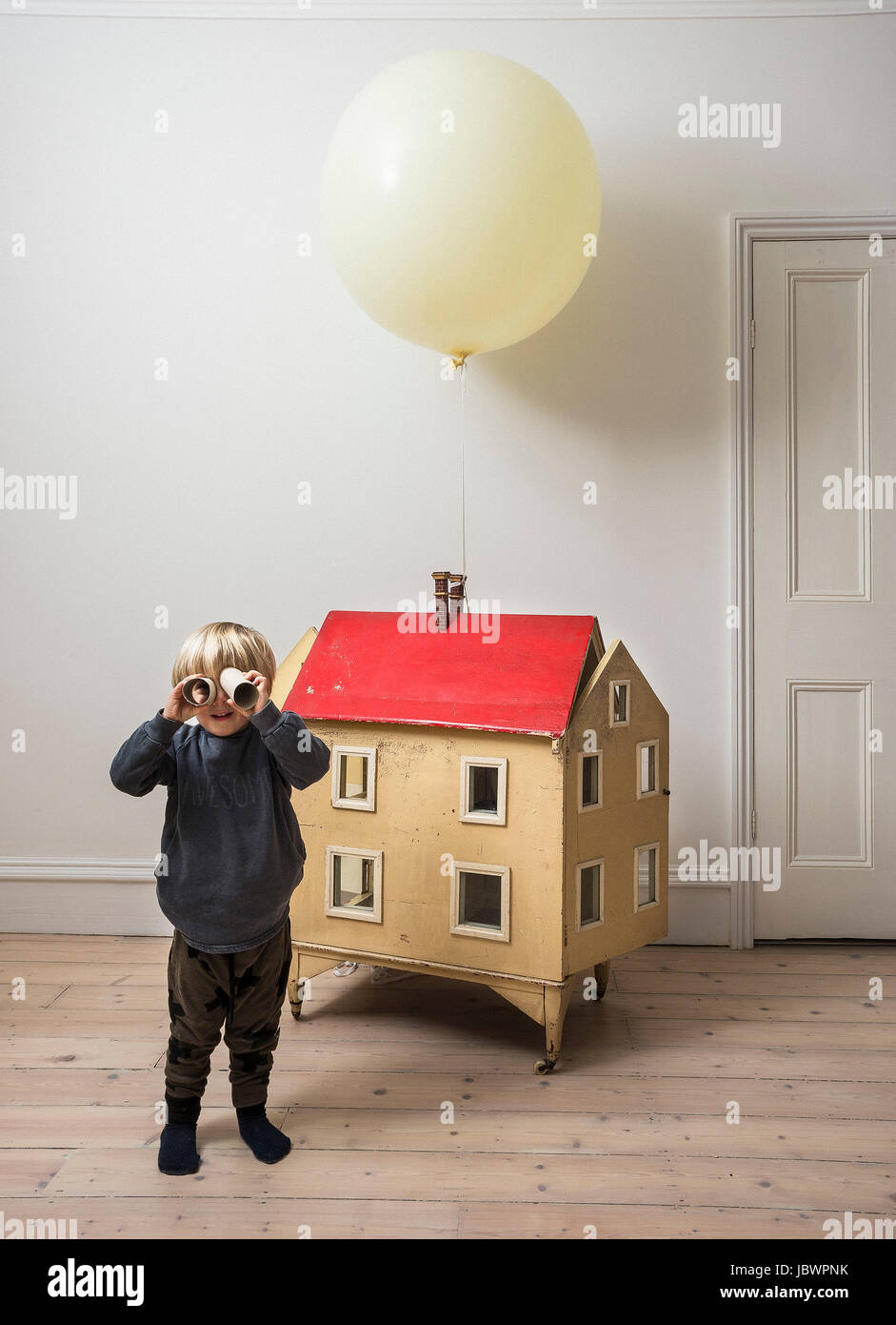 Junge stand neben Puppenhaus Durchsicht Papprohr in die Kamera Stockfoto
