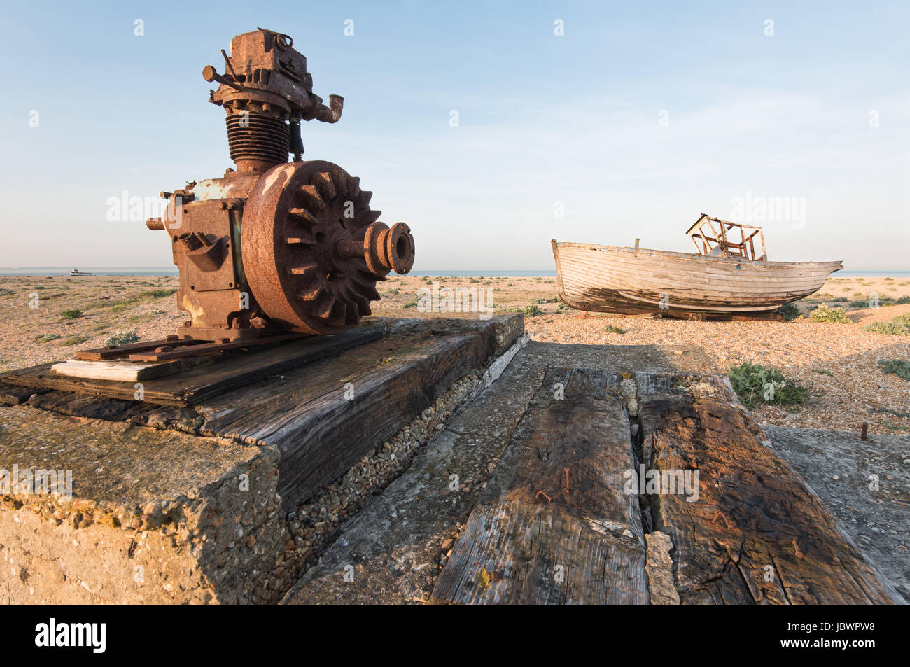 Eine rostigen Seilwinde im linken Vordergrund mit starken führenden Linien, eine verlassene Fischerboot am Strand von Dungeness Stockfoto