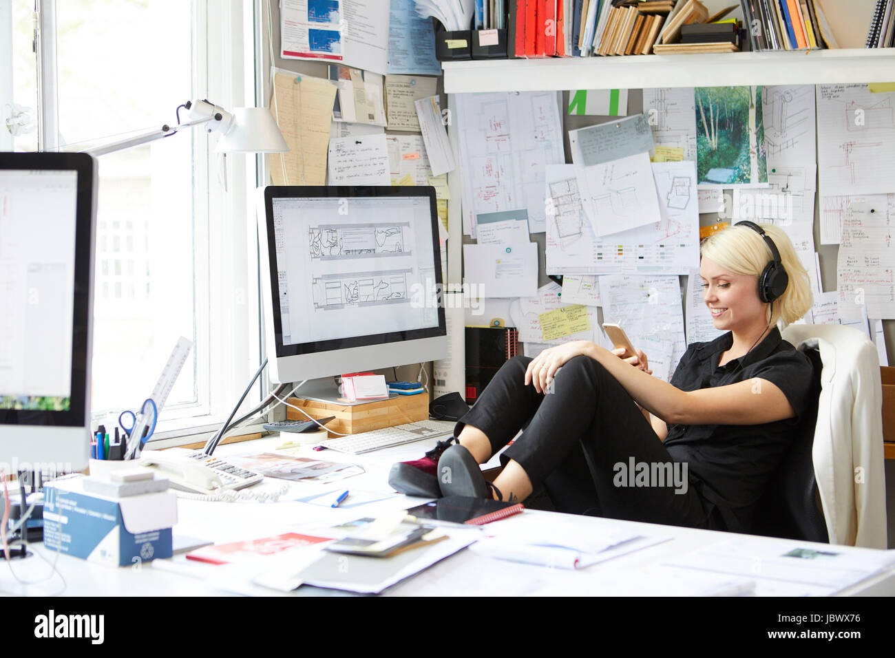 Designerin mit Füßen oben am Schalter Smartphone betrachten Stockfoto