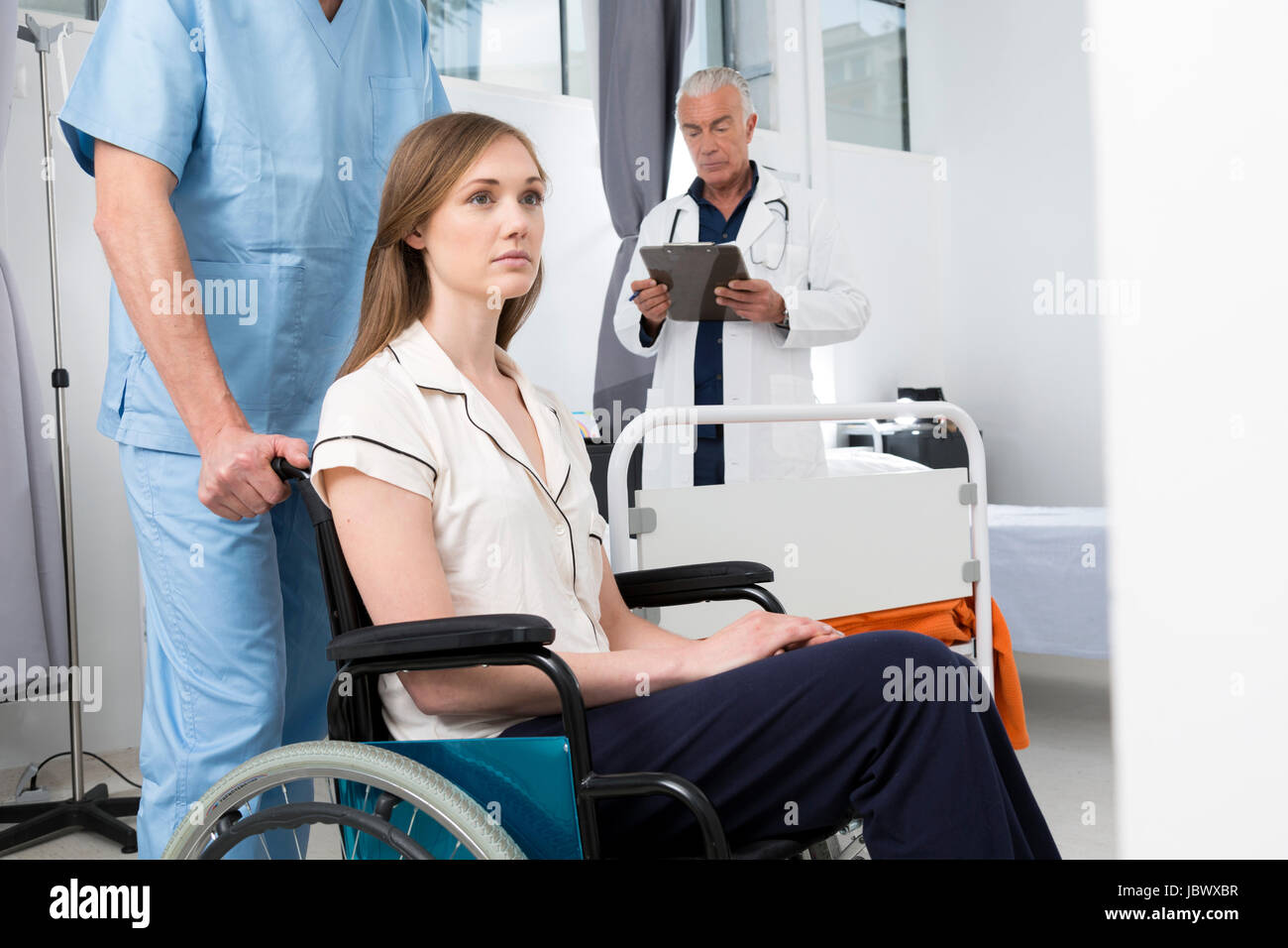 Arzt im Krankenhaus, die Frau im Rollstuhl schieben Stockfoto