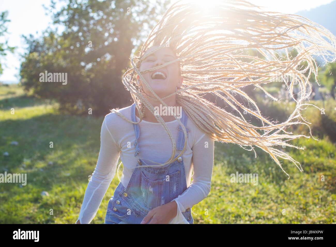 Lustige junge Frau mit langen geflochtenen blonden Haaren im Feld, Mallorca, Spanien Stockfoto