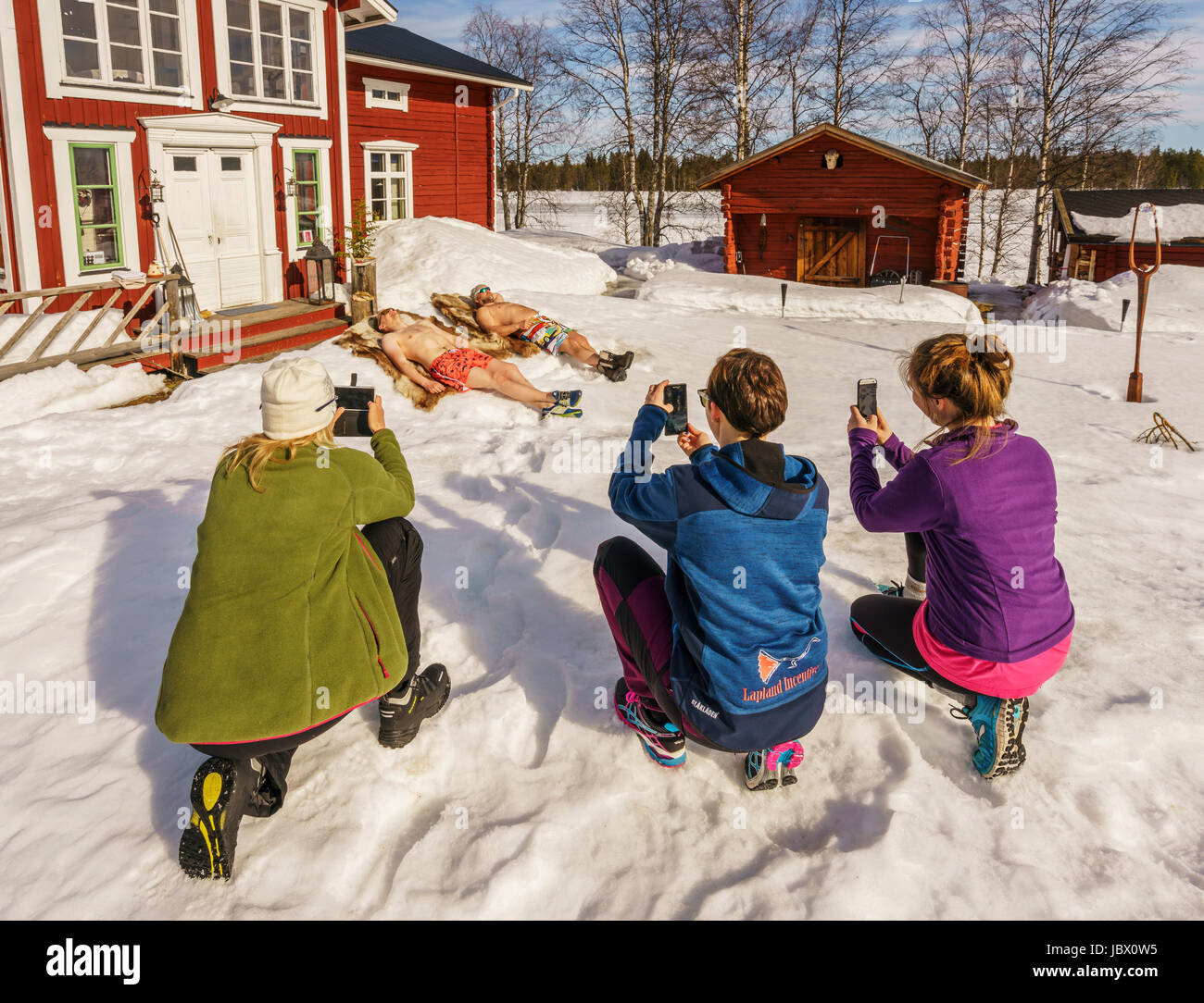 Touristen, die mit Spaß die Bilder von einheimischen Sonnenbaden. Kangos ist eine Ortschaft, gelegen in der Gemeinde Pajala, Norrbotten Grafschaft, Schwedisch-Lappland. Stockfoto