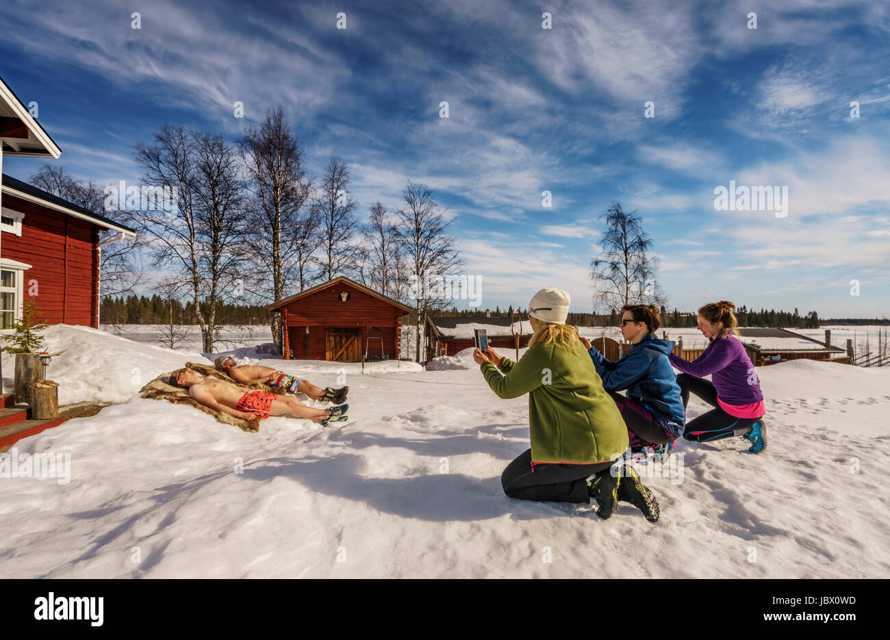Touristen, die mit Spaß die Bilder von einheimischen Sonnenbaden. Kangos ist eine Ortschaft, gelegen in der Gemeinde Pajala, Norrbotten Grafschaft, Schwedisch-Lappland. Stockfoto