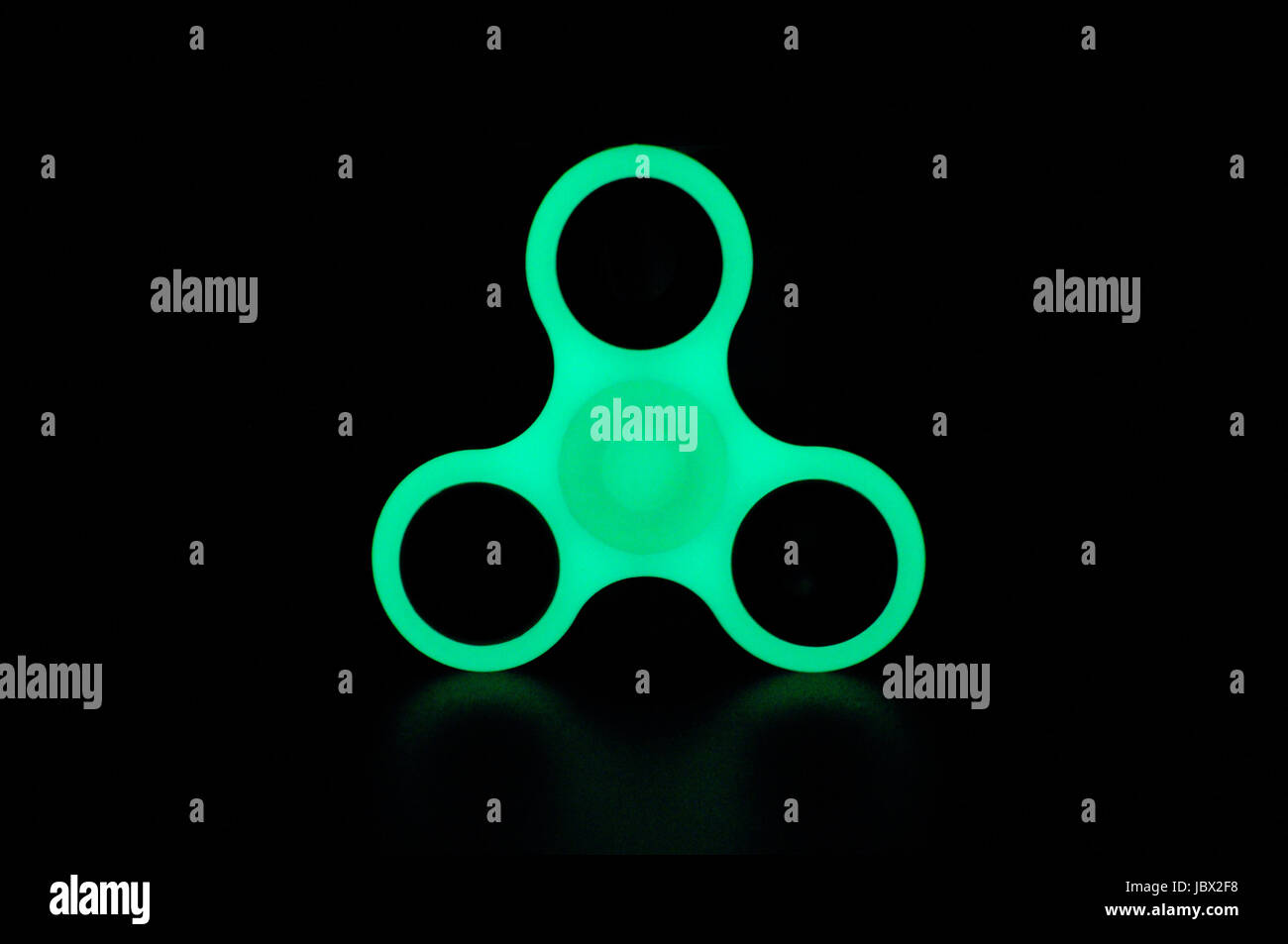 Glühen in den dunklen Fidget Spinner auf schwarzem Hintergrund grün Stockfoto