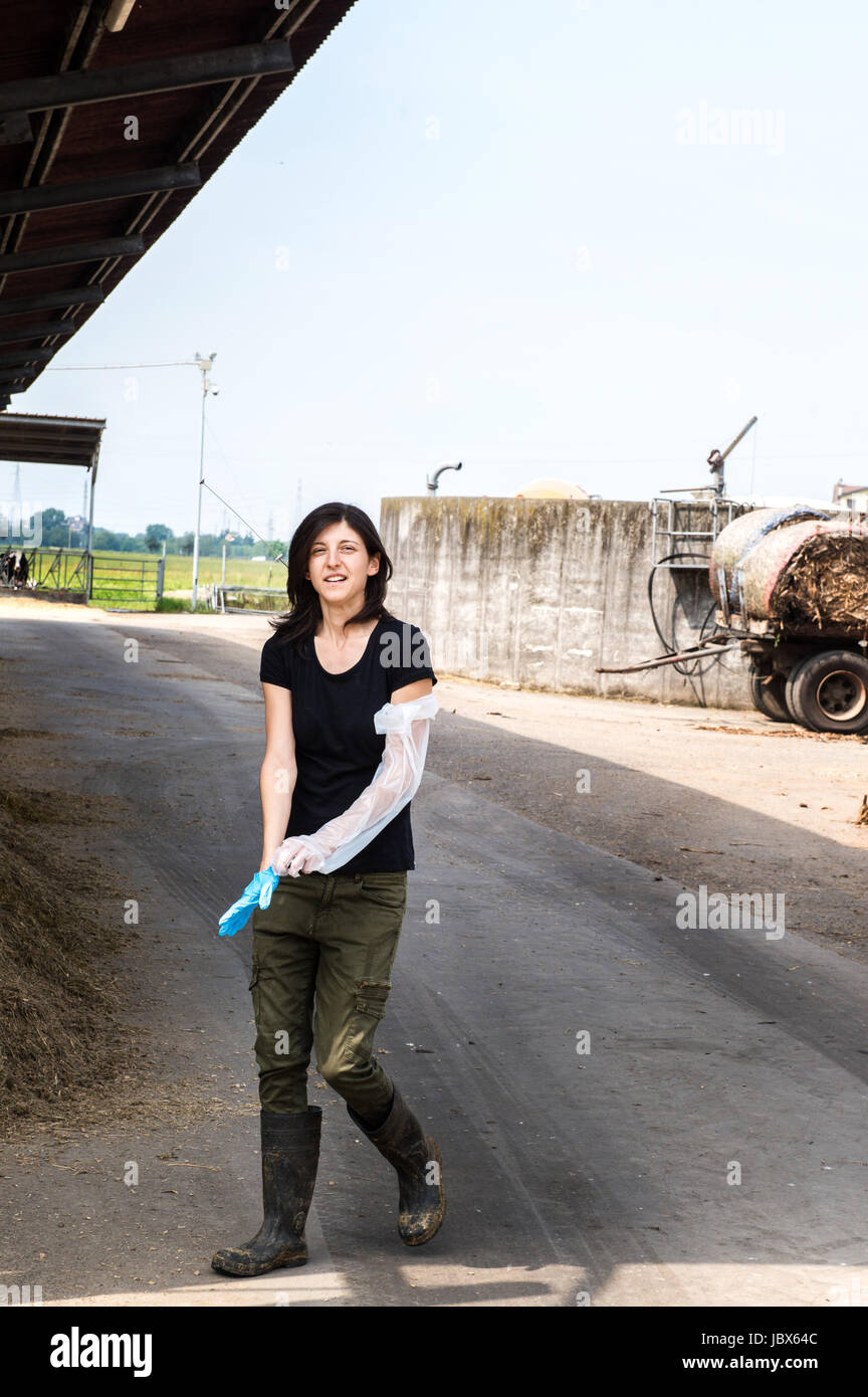 Weibliche Biobauer aufsetzen Schutzhandschuh im Milchviehbetrieb Stockfoto