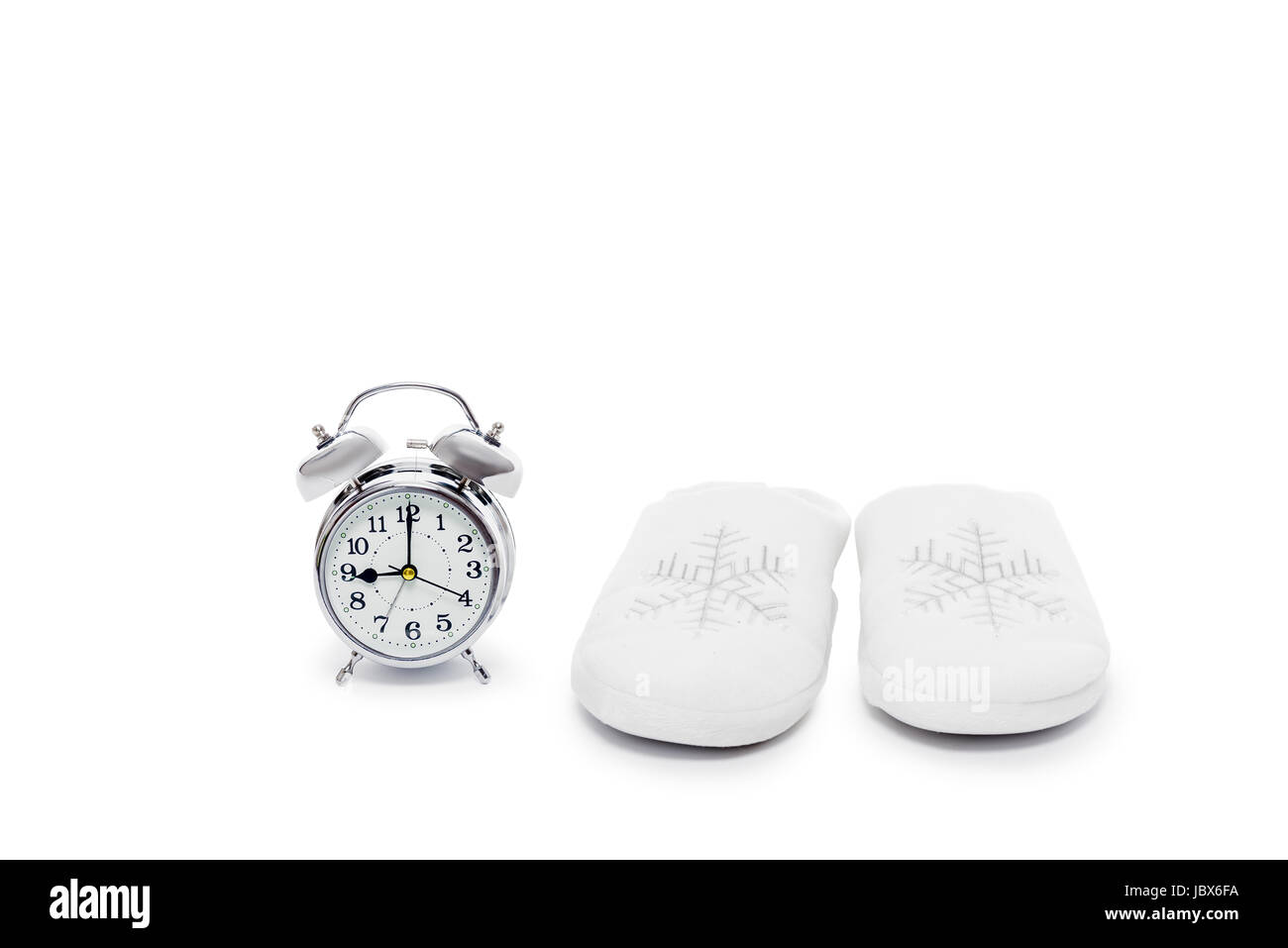 Warmen weißen Hausschuhe und Wecker Nahaufnahme auf weißem Hintergrund Stockfoto