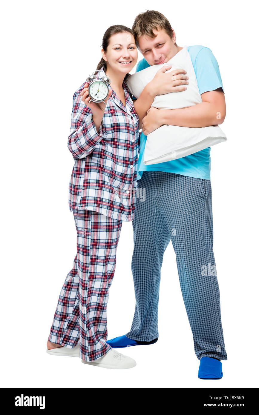 Junges Paar im Pyjama mit Kissen und Wecker auf weißem Hintergrund posiert Stockfoto