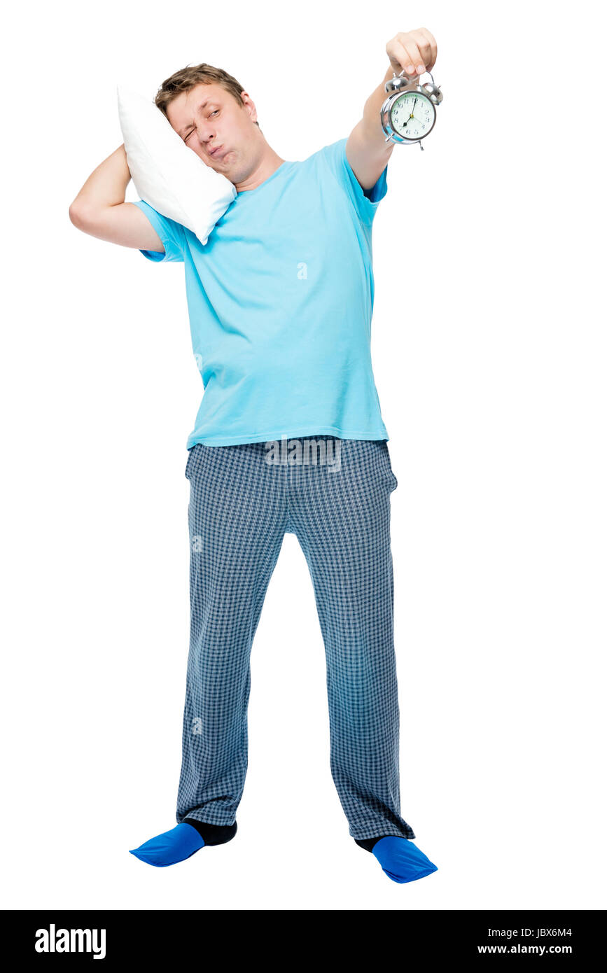 Süße Mann im Pyjama hält einen Wecker in den frühen Morgenstunden auf weißem Hintergrund Stockfoto