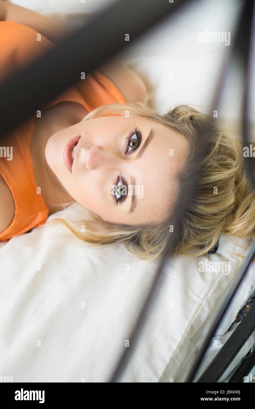 Schöne junge blonde Frau im Bett zur Festlegung Stockfoto