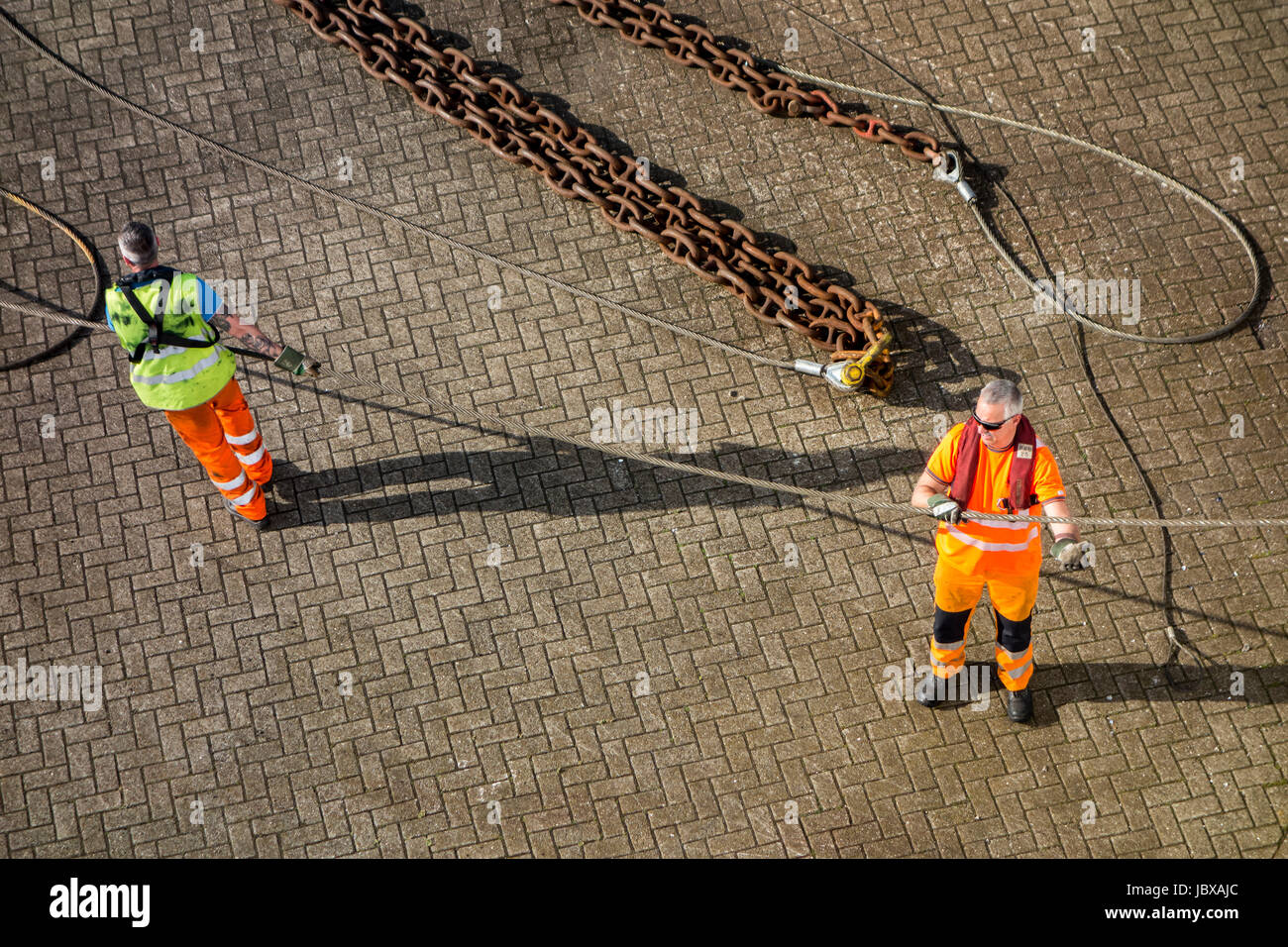 Hafenarbeiter anbringen vertäut Schiffs Trosse Shoreside Bitt auf Kai im Hafen dock Stockfoto