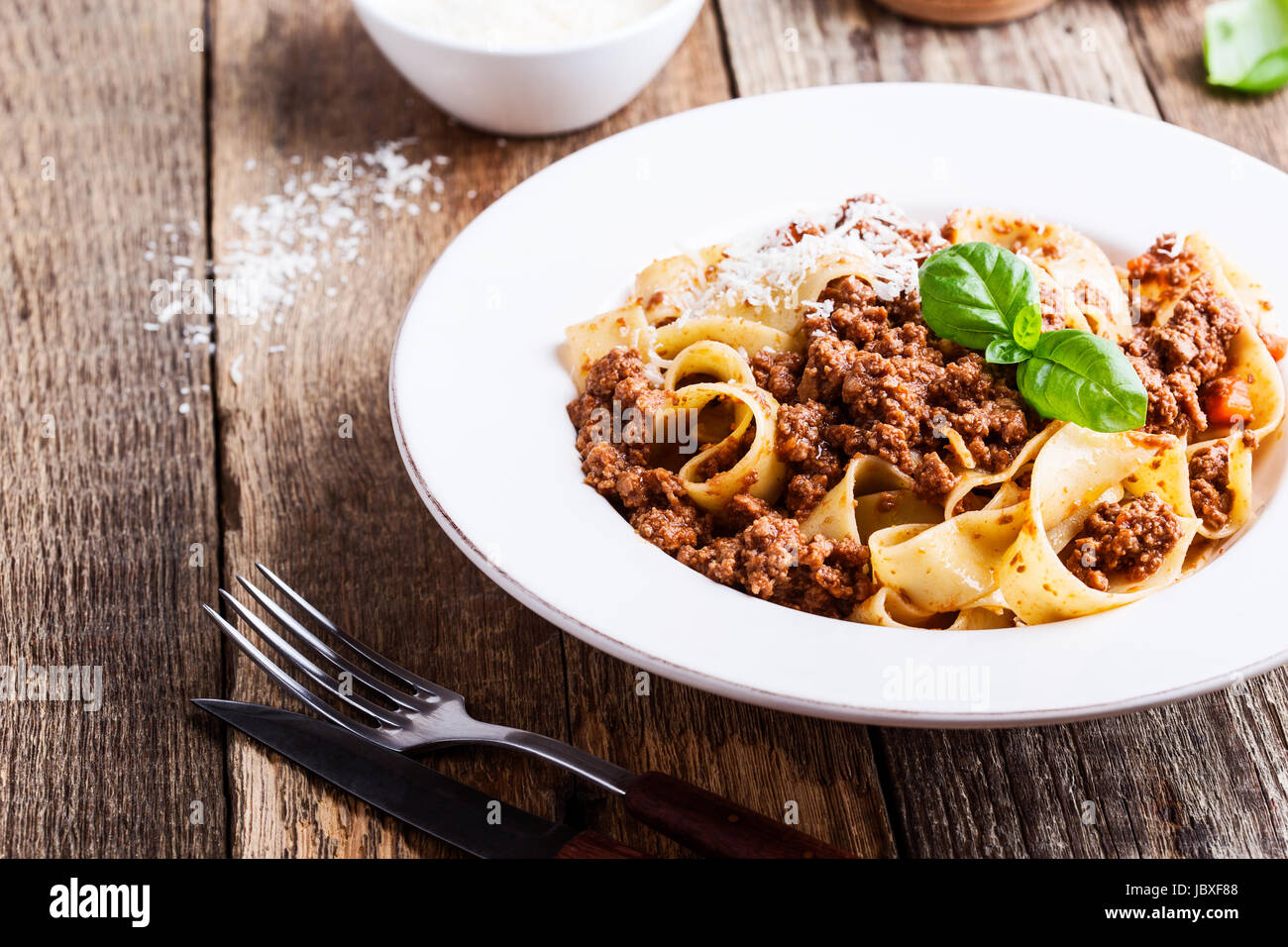 Pasta aus traditionellen italienischen Bandnudeln Bolognese mit Käse Grana Padana auf rustikalen Holztisch serviert Stockfoto