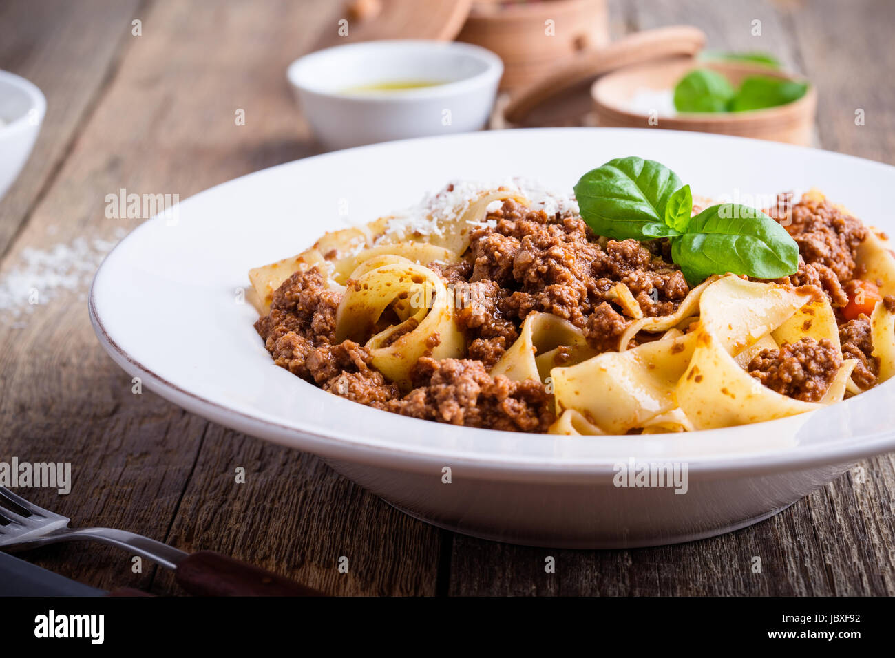 Pasta aus traditionellen italienischen Bandnudeln Bolognese mit Käse Grana Padana auf rustikalen Holztisch serviert Stockfoto