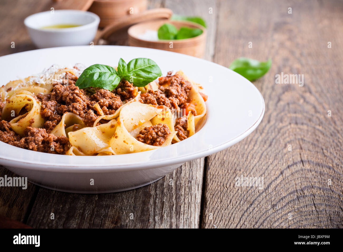 Pasta aus traditionellen italienischen Bandnudeln Bolognese mit Käse Grana Padana auf rustikalen Holztisch serviert Stockfoto