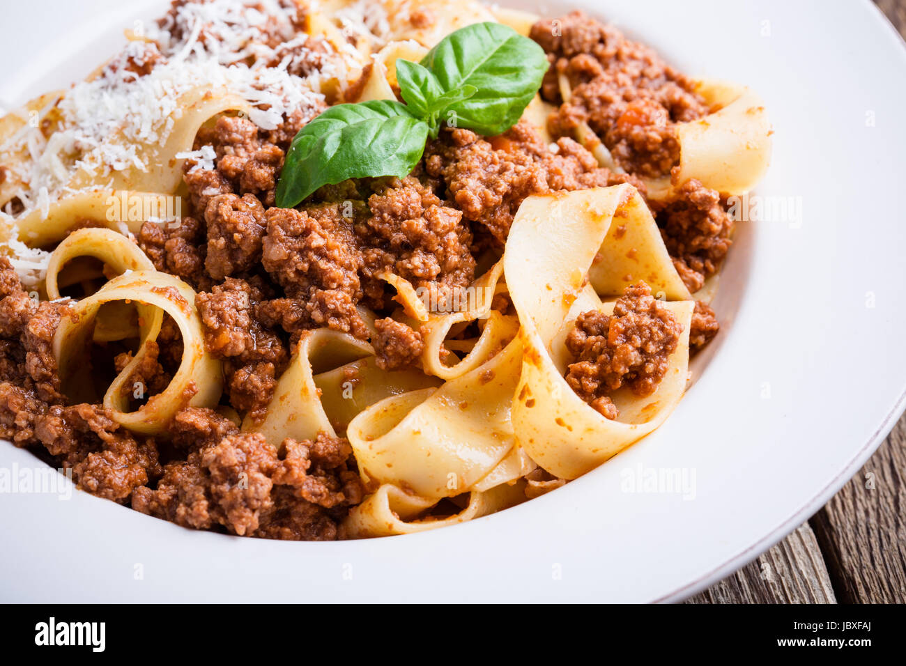Pasta aus traditionellen italienischen Bandnudeln Bolognese mit Käse Grana Padana auf rustikalen Holztisch serviert Stockfoto