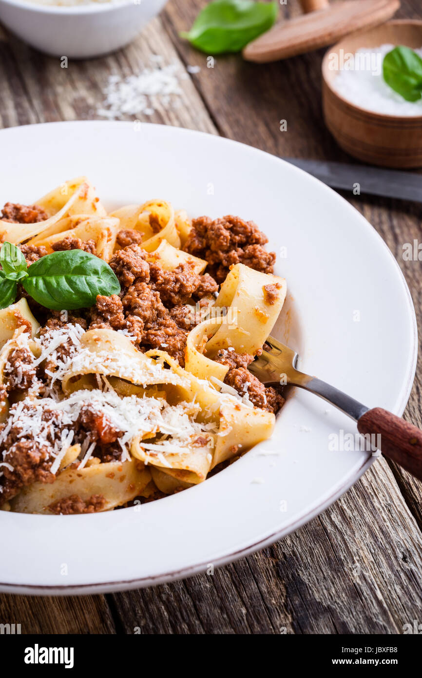 Pasta aus traditionellen italienischen Bandnudeln Bolognese mit Käse Grana Padana auf rustikalen Holztisch serviert Stockfoto