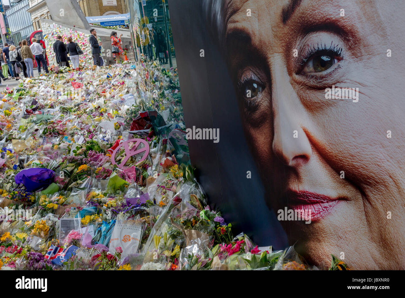 Das Gesicht der Werbung von einer Dame mittleren Alters symbolisiert Mitgefühl und Anteilnahme am Schrein von Blumen und mitfühlende Nachrichten zehn Tage nach dem Attentat auf London Bridge und Borough Market, am 12. Juni 2017 in London, England. Nahe der südlichsten Grenze der City of London gegenüber den Angriff Standort verlassen Londoner und Besucher der Hauptstadt ihre emotionale und trotzig Gedichte und persönliche Mitteilungen. Stockfoto