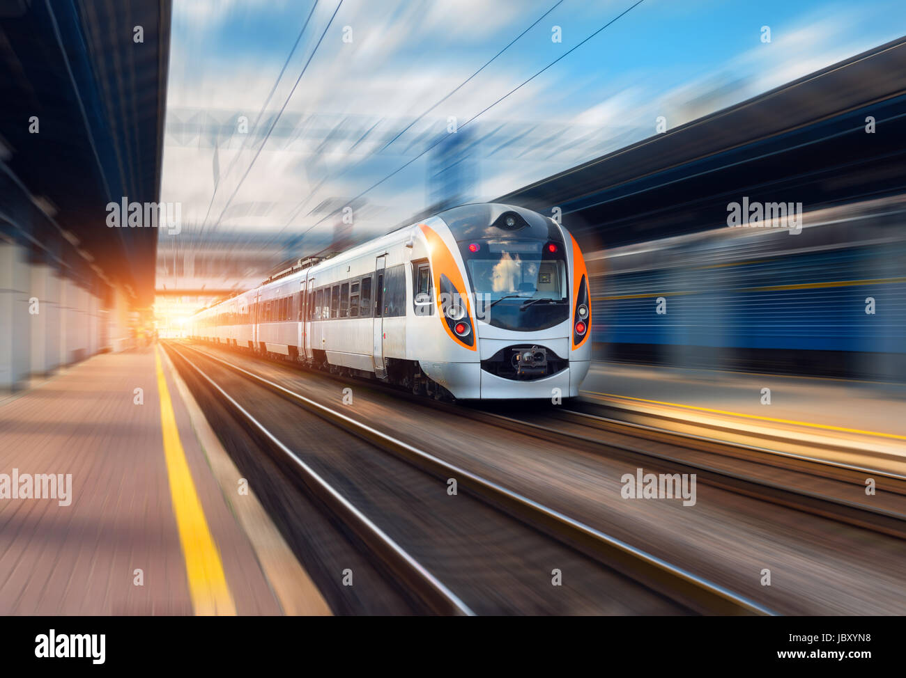 High-Speed-Zug in Bewegung am Bahnhof bei Sonnenuntergang in Europa. Modernen intercity Zug auf dem Bahnsteig mit Motion-Blur-Effekt. Leichtbauteile Stockfoto