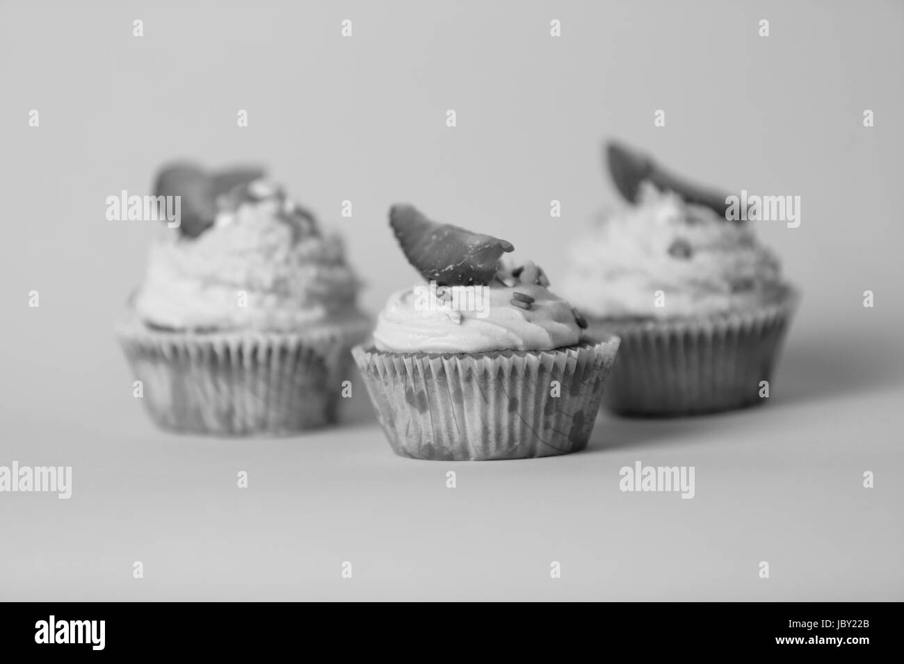 Closeup schwarz-weiß Foto der drei leckere Cupcakes über Hintergrund im studio Stockfoto