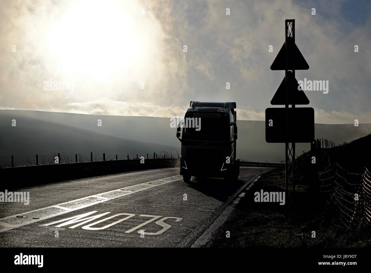 Volvo Sattelzugmaschine Silhouette durch die Sonne rundet eine Biegung auf dem Woodhead-Pass Stockfoto