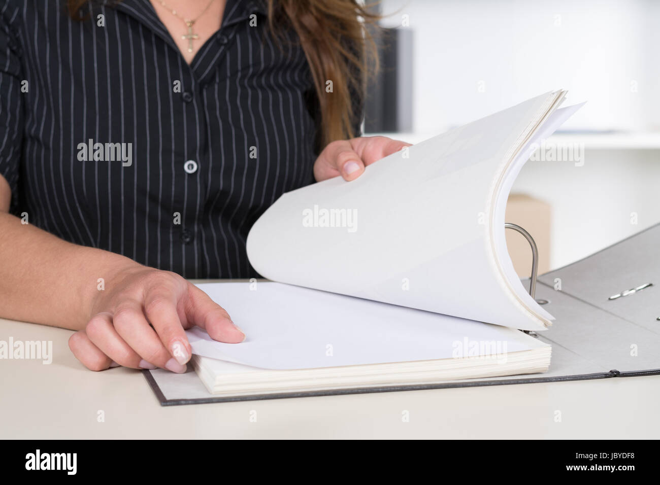 Eine Frau Durchsucht Einen Aktenorder füttere Sie bin Schreibtisch Im Büro Sitzt. Stockfoto